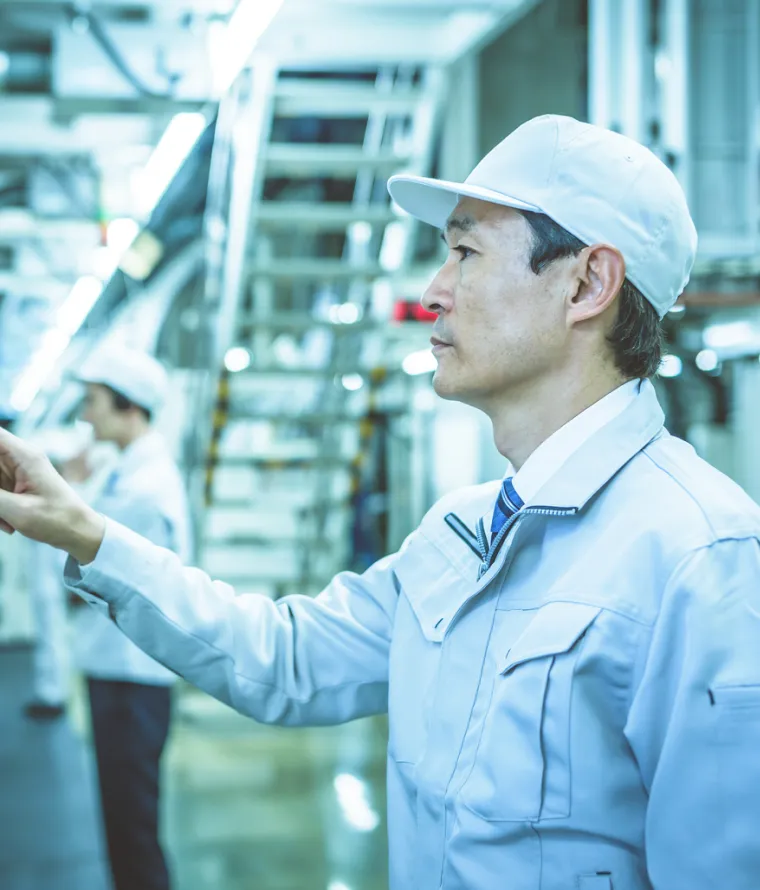 工場で機械のスイッチを押す男性従業員